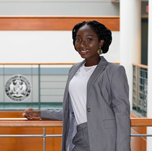 Delle posing at by desk with UMD emblem